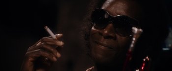 Movie still from “Miles Ahead” (2015), directed by Don Cheadle – A person with sunglasses and a cigarette in their mouth; Close Up shot, Low angle