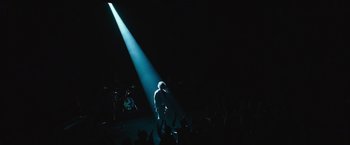 Movie still from “Miles Ahead” (2015), directed by Don Cheadle – A man standing on a stage under a spotlight; Extreme Wide shot, High angle