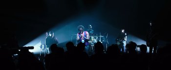 Movie still from “Miles Ahead” (2015), directed by Don Cheadle – A group of people in a room with a microphone; Extreme Wide shot, Low angle