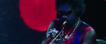 Movie still from “Miles Ahead” (2015), directed by Don Cheadle – A man in sunglasses playing a musical instrument; Close Up shot, Low angle