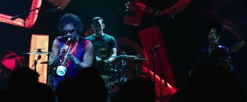 Movie still from “Miles Ahead” (2015), directed by Don Cheadle – A man and a woman playing drums in front of an audience; Medium shot, Low angle