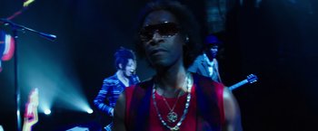 Movie still from “Miles Ahead” (2015), directed by Don Cheadle – A man in a red and blue shirt and sunglasses; Close Up shot, Low angle