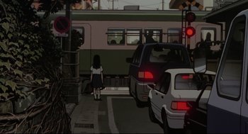 Movie still from “Millennium Actress” (2001), directed by Kô Matsuo – A girl is walking down the street in front of a train; Wide shot, Low angle