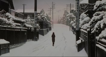 Movie still from “Millennium Actress” (2001), directed by Kô Matsuo – A person walking down a snow covered street; Extreme Wide shot, Low angle