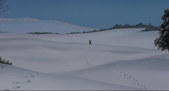 Movie still from “Millennium Actress” (2001), directed by Kô Matsuo – A person is walking through the snow on a hill; Extreme Wide shot, High angle