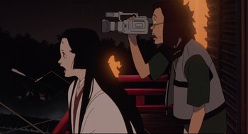 Movie still from “Millennium Actress” (2001), directed by Kô Matsuo – A person holding a video camera in front of another person; Medium shot, Low angle