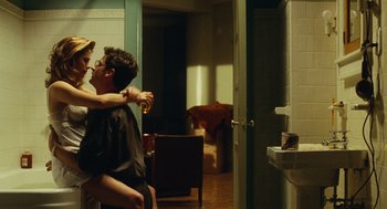 Movie still from “Mimic” (1997), directed by Guillermo del Toro – A man sitting in a chair with a woman in a bathroom; Wide shot, Over the shoulder angle