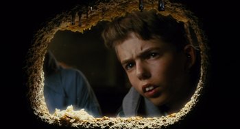 Movie still from “Mimic” (1997), directed by Guillermo del Toro – A young boy looking into a hole in the ground; Close Up shot, Low angle