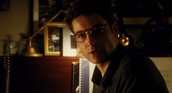 Movie still from “Mimic” (1997), directed by Guillermo del Toro – A man wearing glasses and a black shirt is looking at the camera; Close Up shot, Over the shoulder angle