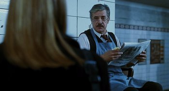 Movie still from “Mimic” (1997), directed by Guillermo del Toro – An older man sitting in front of a woman holding a sandwich; Medium shot, Over the shoulder angle