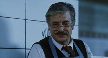 Movie still from “Mimic” (1997), directed by Guillermo del Toro – An older man with a mustache wearing a vest and tie; Close Up shot, Low angle