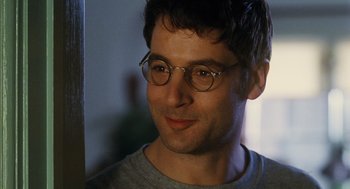 Movie still from “Mimic” (1997), directed by Guillermo del Toro – A person wearing glasses and smiling; Close Up shot, Over the shoulder angle