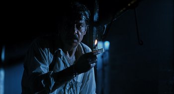 Movie still from “Mimic” (1997), directed by Guillermo del Toro – A man holding a cell phone in his hand; Close Up shot, Low angle