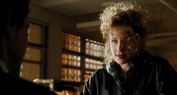 Movie still from “Mimic” (1997), directed by Guillermo del Toro – A woman with curly blonde hair is standing in a room; Close Up shot, Over the shoulder angle