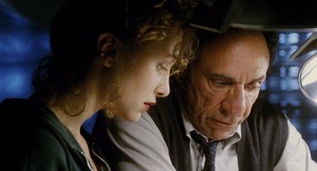 Movie still from “Mimic” (1997), directed by Guillermo del Toro – An older man and a young woman sitting next to each other; Close Up shot, High angle
