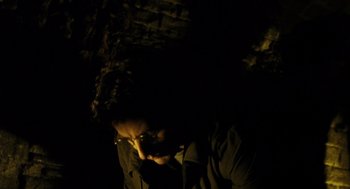 A man in a dark room looking down at the ground