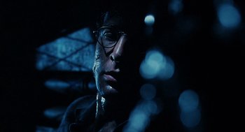 Movie still from “Mimic” (1997), directed by Guillermo del Toro – A person wearing glasses and a jacket; Close Up shot, Low angle