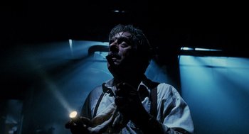 Movie still from “Mimic” (1997), directed by Guillermo del Toro – A man holding a candle in a dimly - lit room; Close Up shot, Low angle