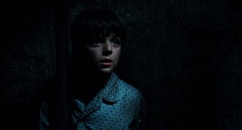 Movie still from “Mimic” (1997), directed by Guillermo del Toro – A young boy standing in a dark room with his eyes closed; Close Up shot, High angle