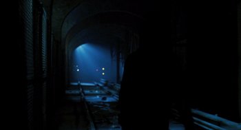 Movie still from “Mimic” (1997), directed by Guillermo del Toro – A person is standing in a dark tunnel; Wide shot, Over the shoulder angle