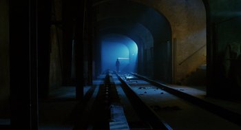 Movie still from “Mimic” (1997), directed by Guillermo del Toro – A man standing on a train track in a tunnel; Extreme Wide shot, High angle