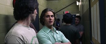 Movie still from “Miracle” (2004), directed by Gavin O'Connor – A man with long hair and a green shirt is standing next to another man; Close Up shot, Over the shoulder angle