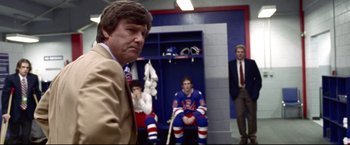 Movie still from “Miracle” (2004), directed by Gavin O'Connor – A man in a suit and tie in front of two hockey players; Medium shot, Over the shoulder angle