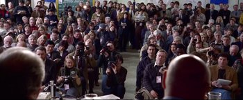 Movie still from “Miracle” (2004), directed by Gavin O'Connor – A group of people sitting in a room taking pictures; Wide shot, High angle