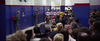 Movie still from “Miracle” (2004), directed by Gavin O'Connor – A group of men walking down a hallway in front of a crowd of onlookers; Wide shot, Over the shoulder angle