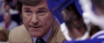 Movie still from “Miracle” (2004), directed by Gavin O'Connor – An older man wearing a suit and tie holding an umbrella; Close Up shot, Over the shoulder angle