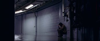 Movie still from “Miracle” (2004), directed by Gavin O'Connor – A man sitting on the ground in a building; Wide shot, High angle