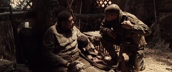 Movie still from “Miracle at St. Anna” (2008), directed by Spike Lee – Two men are sitting on a bed in a cave; Medium shot, High angle