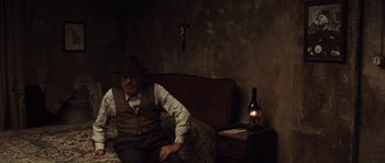 Movie still from “Miracle at St. Anna” (2008), directed by Spike Lee – A man sitting on a couch next to a cross; Medium shot, High angle