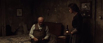 Movie still from “Miracle at St. Anna” (2008), directed by Spike Lee – An older man sitting on a bed next to a woman; Medium shot, Over the shoulder angle