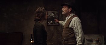 Movie still from “Miracle at St. Anna” (2008), directed by Spike Lee – An older man and a young woman standing next to each other in front of a painting; Medium shot, Over the shoulder angle