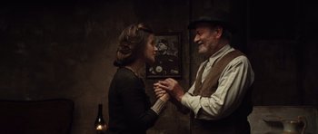 Movie still from “Miracle at St. Anna” (2008), directed by Spike Lee – An older man and a younger woman holding hands in front of a portrait; Medium shot, Over the shoulder angle