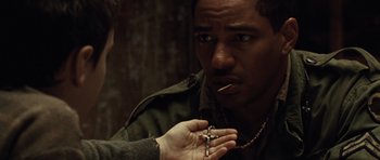 Movie still from “Miracle at St. Anna” (2008), directed by Spike Lee – A man holding a cross with a cigarette in his mouth; Close Up shot, Over the shoulder angle