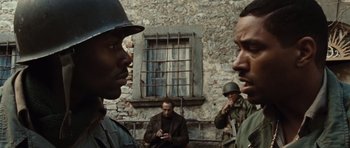 Movie still from “Miracle at St. Anna” (2008), directed by Spike Lee – A group of men standing next to each other in front of a brick building; Close Up shot, Over the shoulder angle