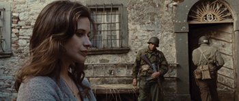 Movie still from “Miracle at St. Anna” (2008), directed by Spike Lee – A woman standing next to a man holding a gun; Medium shot, Over the shoulder angle