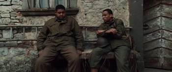 Movie still from “Miracle at St. Anna” (2008), directed by Spike Lee – A couple of men sitting next to each other on top of a bench; Medium shot, Low angle