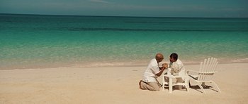Movie still from “Miracle at St. Anna” (2008), directed by Spike Lee – A man kneeling down at a table on the beach; Wide shot, High angle