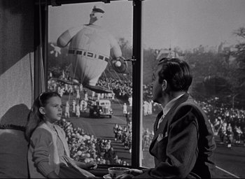Movie still from “Miracle on 34th Street” (1947), directed by George Seaton – A man and a girl watching a balloon float in the air; Wide shot, Low angle