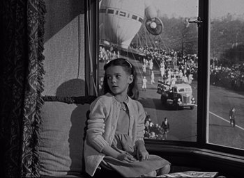 Movie still from “Miracle on 34th Street” (1947), directed by George Seaton – A young girl sitting on a couch looking out of a window; Medium shot, Low angle
