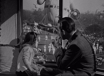 Movie still from “Miracle on 34th Street” (1947), directed by George Seaton – A man and a little girl sitting next to each other in front of an airplane; Wide shot, Low angle