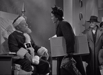 Movie still from “Miracle on 34th Street” (1947), directed by George Seaton – An old photo of a man and a woman sitting in a chair; Medium shot, High angle