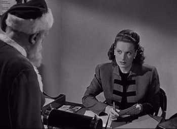 Movie still from “Miracle on 34th Street” (1947), directed by George Seaton – An old photo of a woman sitting at a table with a santa clause; Medium shot, High angle