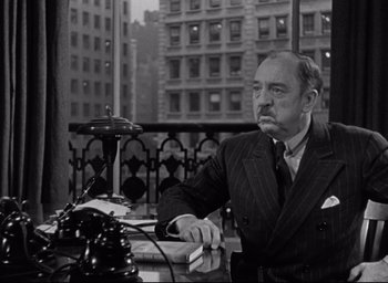 Movie still from “Miracle on 34th Street” (1947), directed by George Seaton – An older man sitting at a table in a suit; Medium shot, High angle