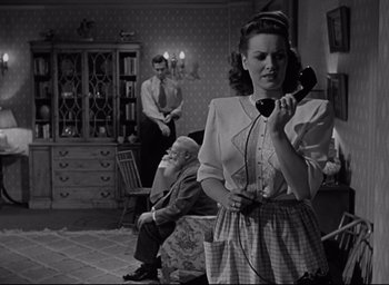 Movie still from “Miracle on 34th Street” (1947), directed by George Seaton – A woman holding a phone while sitting on a chair; Medium shot, Low angle