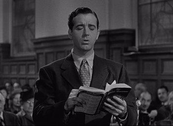 Movie still from “Miracle on 34th Street” (1947), directed by George Seaton – A black and white photo of a man reading a book; Close Up shot, Low angle