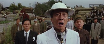 Movie still from “Miracles: The Canton Godfather” (1989), directed by Jackie Chan – A man in a white suit and a white hat; Close Up shot, Low angle